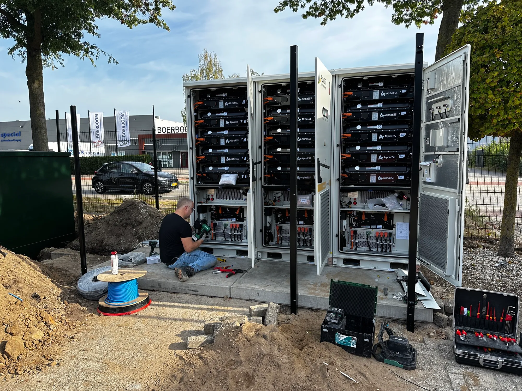 Monteur werkt aan drie geopende batterijcontainers op locatie